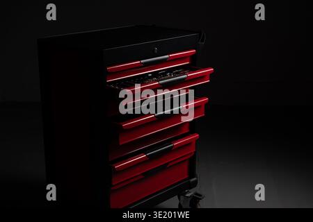 Red metal tool chest with several open drawers revealing organized mechanic tools in a dark workshop. Industrial tool storage and professional garage Stock Photo