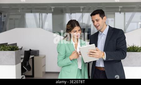 Confident business professional mentoring female coworker using tablet in office Stock Photo