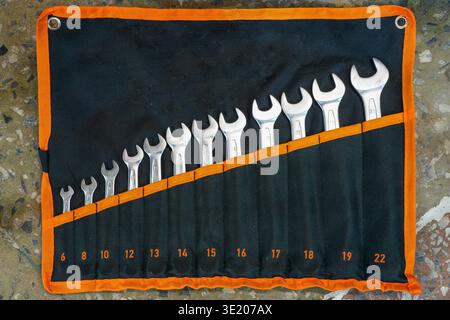 Top view of open-end wrench set arranged in a fabric tool roll with metric sizes, used for automotive repair and maintenance Stock Photo