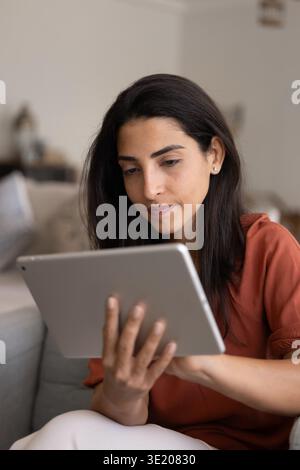 Close-up of young focused woman using digital tablet at home Stock Photo