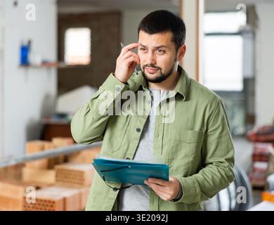 Architect making notes on indoor construction site Stock Photo