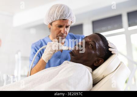African American man undergoing cosmetic facial procedure using ion bubble pen Stock Photo