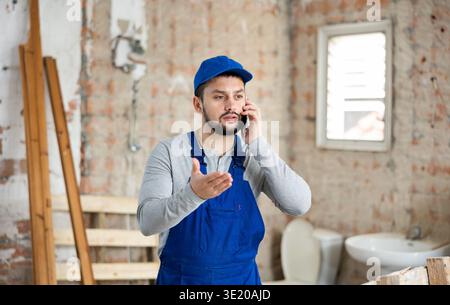 Young builder talking on phone in building under renovation Stock Photo