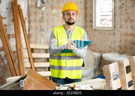 Builder making notes on indoor construction site Stock Photo