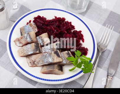 Slightly salted herring slices with grated beets and greens Stock Photo