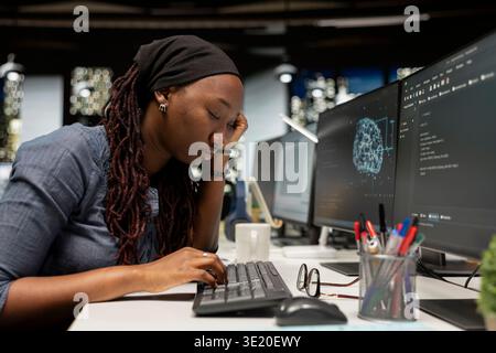 Tired software developer falling asleep on desk in AI startup office, needing break to recover. Employee feeling sleepy, lacking energy after sleepless night, closing eyes to eliminate fatigue Stock Photo