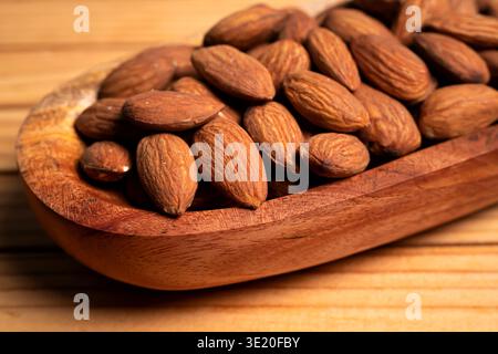 Close up Of A Wooden Spoon Filled With Whole Almonds On A Textured Wood Surface Stock Photo