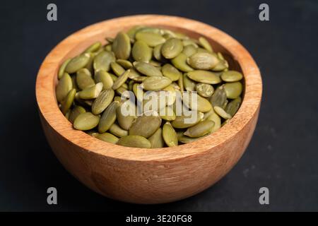 Wooden Bowl Filled With Roasted Pumpkin Seeds With Salt Sprinkled On Top Against A Dark Background Stock Photo