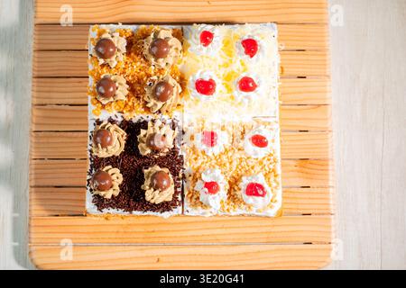 Four Different Mini Cakes Assortment Displayed on a Wooden Board with Cream Frosting and Toppings Top View Stock Photo