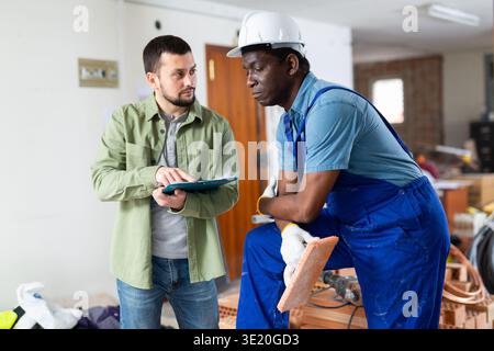 Engineer shows the estimate to a builder, explaining the working moments Stock Photo