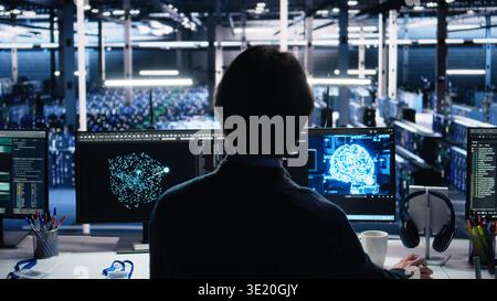 Software developer in data center coding with generative AI assistance. IT specialist leveraging artificial intelligence large language model to solve tasks in server farm, camera A Stock Photo