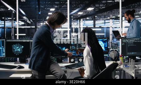 Senior engineer and trainee in data center working on neural network software development. Lead programmer and intern in server room implementing machine learning technology using PC, camera A Stock Photo