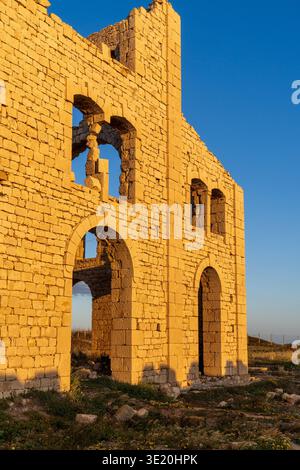 Close-up view of the Fornace Penna in Sampieri, Sicily. The image highlights the texture of the limestone gilded by the sunset, with the iconic arched Stock Photo