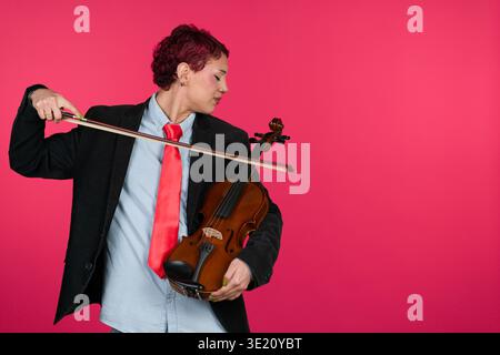Person holding violin and bow on pink backdrop Stock Photo