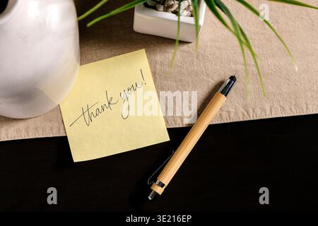 Thank you message on yellow sticky note with pen on desk, gratitude and appreciation concept. Stock Photo