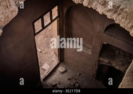 Interior view of a crumbling entrance in an abandoned mud-brick house in an Iranian desert village, highlighting the traditional adobe architecture an Stock Photo