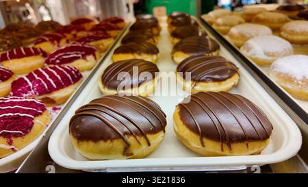 Donuts with chocolate icing and pink toppings on display Stock Photo