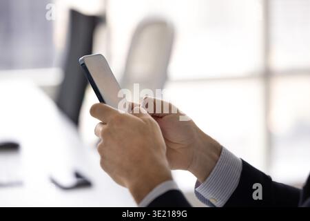 Close up businessman hands holding modern mobile phone in office Stock Photo
