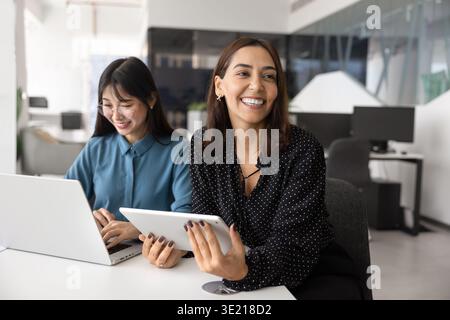 Cheerful Middle Eastern business professional woman sitting at meeting table Stock Photo