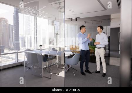 Two multicultural businessmen communicating in spacious modern glass conference room Stock Photo