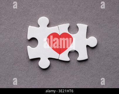 Collage of Heart Puzzle Pieces Fitting Together on a Gray Background in a Simple Design Stock Photo