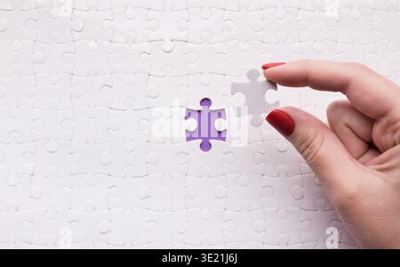 Hand Places Puzzle Piece in Blank Collage Demonstrating Completion of a Set Stock Photo