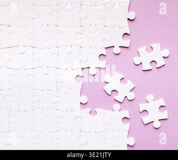 Collage Showing Pieces of a White Puzzle on a Purple Background With Scattered Pieces Stock Photo