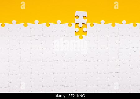Collection of Blank Puzzle Pieces on a Yellow Background With One Piece Missing From the Set Stock Photo