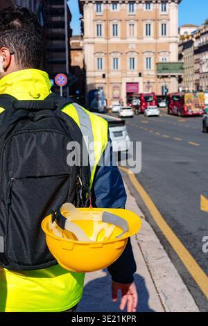 Worker walks along city street with a yellow hard hat after finishing work Stock Photo
