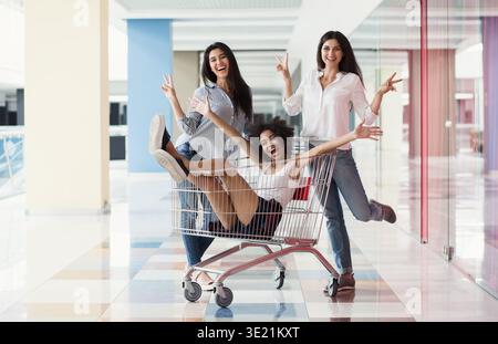 Multiracial girls having fun with supermarket trolley Stock Photo