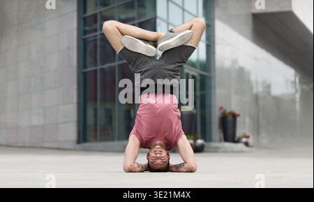 Professional yoga man doing headstand exercise outdoors Stock Photo