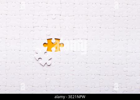 Collection of White Puzzle Pieces With One Yellow Piece and a Missing Spot Stock Photo