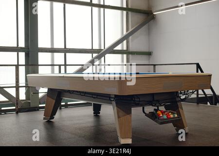Modern Billiard Table Standing Empty in Sunlit Industrial Recreation Room Stock Photo
