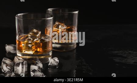 Two glasses of whiskey and ice on black background Stock Photo