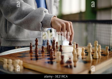Young Adult Man Strategizing Move While Playing Chess Indoors Stock Photo