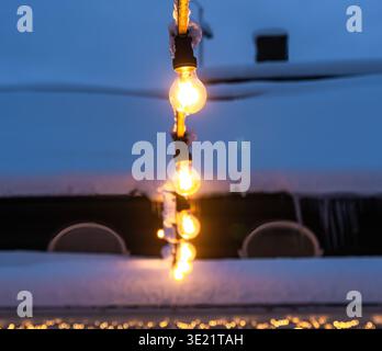 String lights glowing warmly in a snowy winter setting. Stock Photo