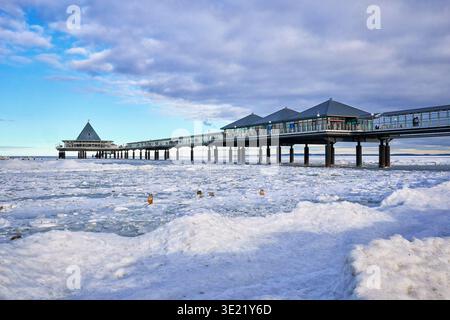 The iconic Seebruecke Heringsdorf pier extends over the icy, frozen Baltic Sea during winter on Usedom Island, Mecklenburg-Vorpommern, Germany. A pict Stock Photo