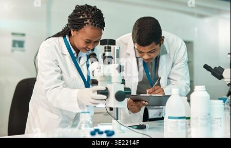 Microscope, writing and scientists with research in lab, study pathogens and teamwork for results report. Investigation, trial notes and people with Stock Photo