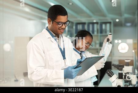 Their investigation is underway. Shot of a young scientist writing notes while working with a colleague in a lab. Stock Photo