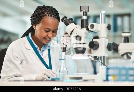 Black woman, scientist and pipette with sample in lab for chemistry, research and medical study. Female person, microscope and liquid for testing Stock Photo