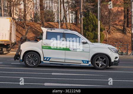 Yongin, South Korea: White tow truck with green "promy" and "DB손해보험" branding driving on city road in Yongin district, Seoul. Stock Photo