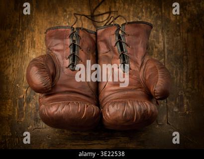 Pair of old brown leather boxing gloves lying on an antique wooden table Stock Photo