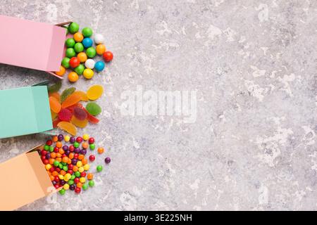 Colorful candies scattering from paper boxes on concrete background Stock Photo