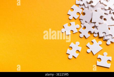 Collection of White Puzzle Pieces Displayed on a Bright Orange Background in a Creative Layout Stock Photo