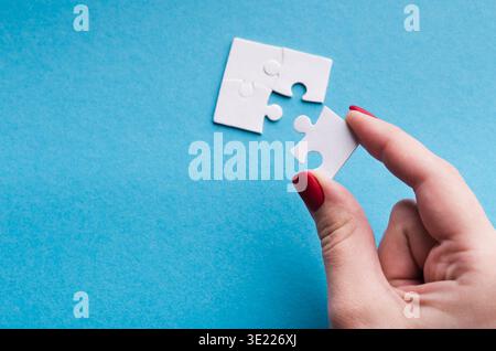 Hand Holding Puzzle Piece in Collage Setting With Light Blue Background and Additional Pieces Near Stock Photo