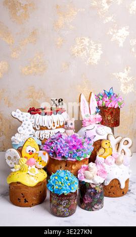 Luxurious collection of hand-decorated Easter kulichi with colorful icings, fondant figures. Spring holiday composition on golden-beige background, pe Stock Photo
