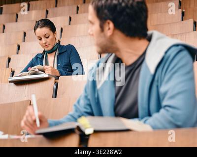 Two students studying in a college lecture hall with notebooks and focus on their work. Germany Stock Photo