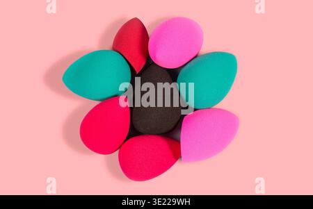 Colorful blending sponges arranged in a circular pattern on a pink background Stock Photo