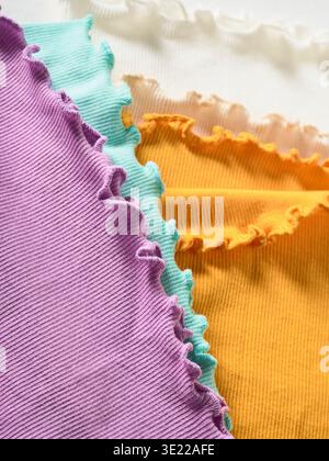 Colorful fabric swatches with ruffled edges in purple, teal, orange, and cream. Germany Stock Photo