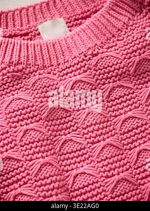 Pink knitted sweater with intricate textured patterns and ribbed collar. Germany Stock Photo